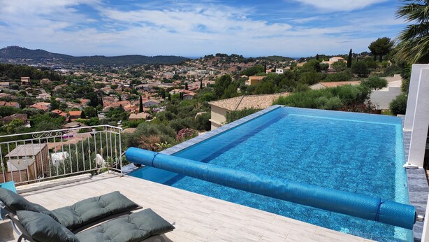 Una piscina infinita en la azotea con vistas a un pueblo y colinas.
