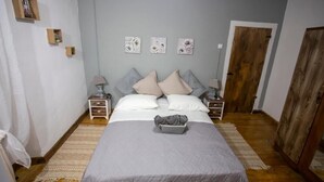 A bedroom with a bed, two bedside tables, a nightstand, a wooden wardrobe, and a door. - Archontissa Sea View House (Mesongi)
