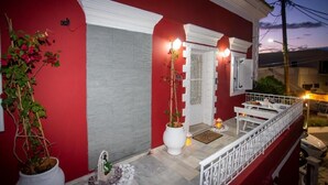 A red building with a white porch and a white railing. - Archontissa Sea View House (Mesongi)