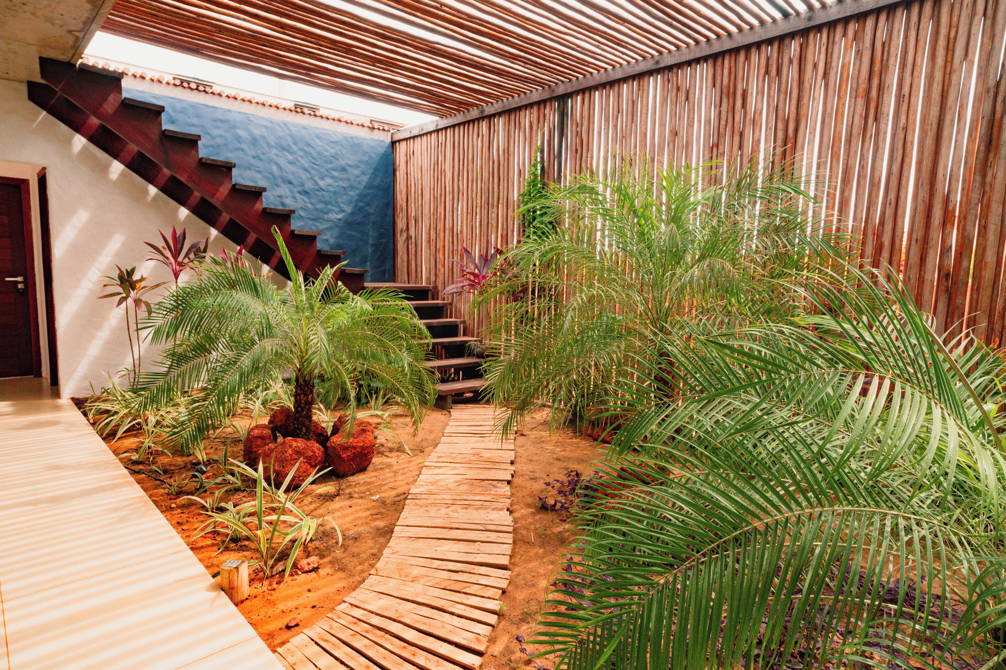 Eine Holzterrasse, die zu einer Treppe führt, umgeben von üppiger tropischer Vegetation.