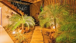 A wooden pathway leading to a staircase surrounded by lush greenery and rocks. - Santa Maria Inn (Sao Miguel do Gostoso)