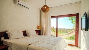 A bedroom with a large bed, a hanging light fixture, and a view of the outdoors through a sliding glass door. - Santa Maria Inn (Sao Miguel do Gostoso)