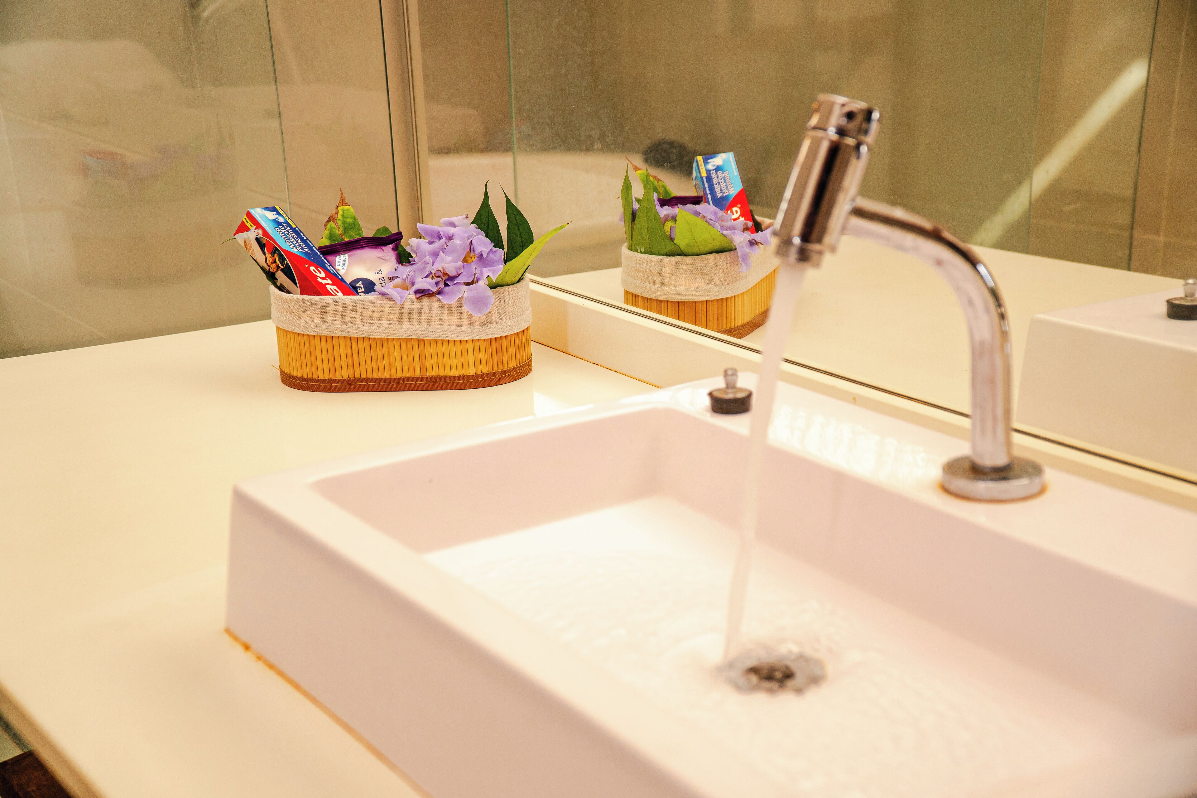 A bathroom sink with a mirror above it, a toothbrush holder with a toothbrush, and a cup of coffee.