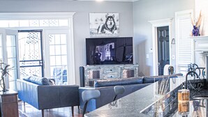 Un salón amplio con un televisor grande, un sofá y una mesa de centro.