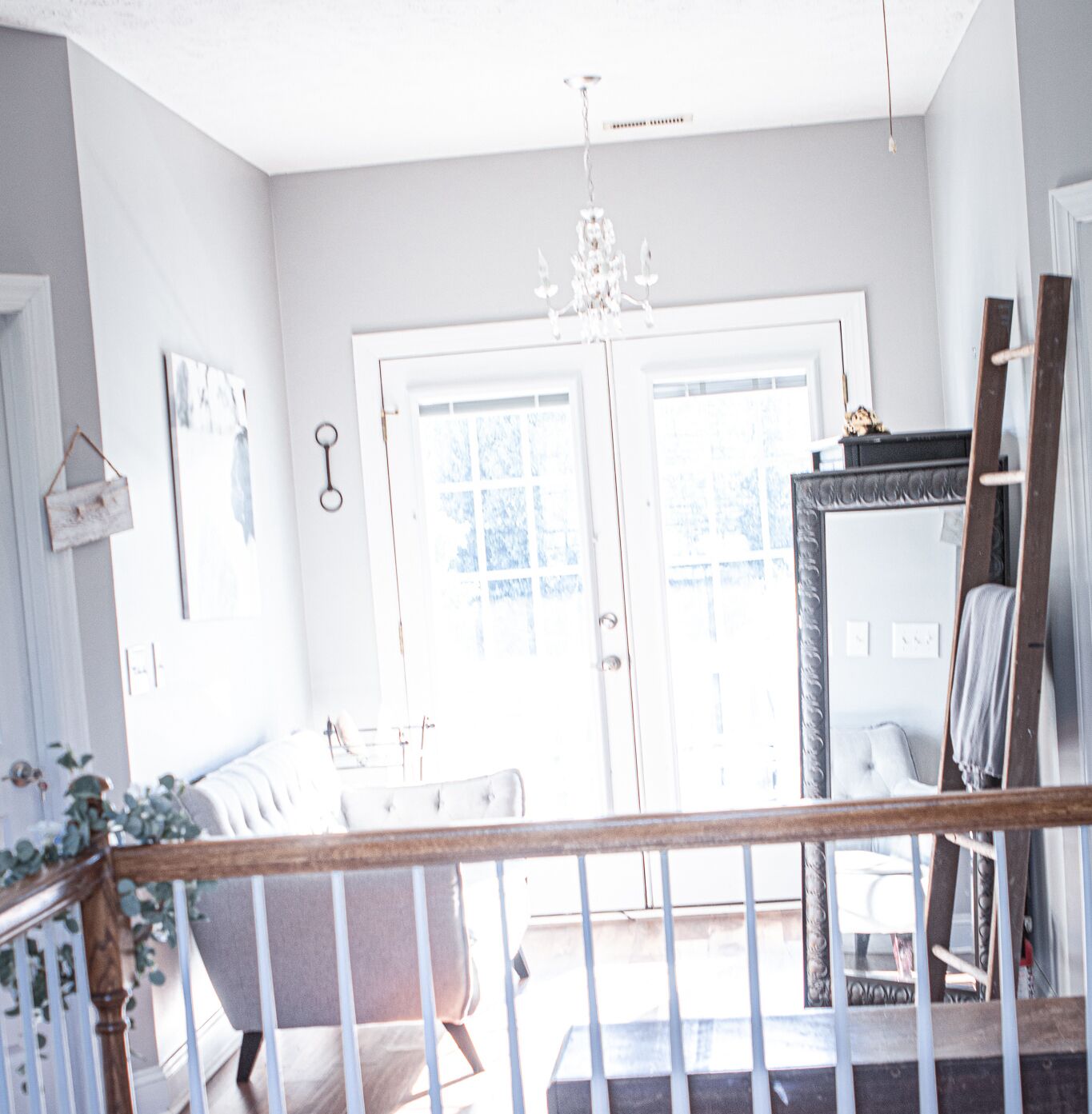 A bright room with a chandelier, a white door, and a mirror on the wall.