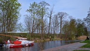Een rode boot afgemeerd aan een steiger met een duidelijke looppad ernaast.