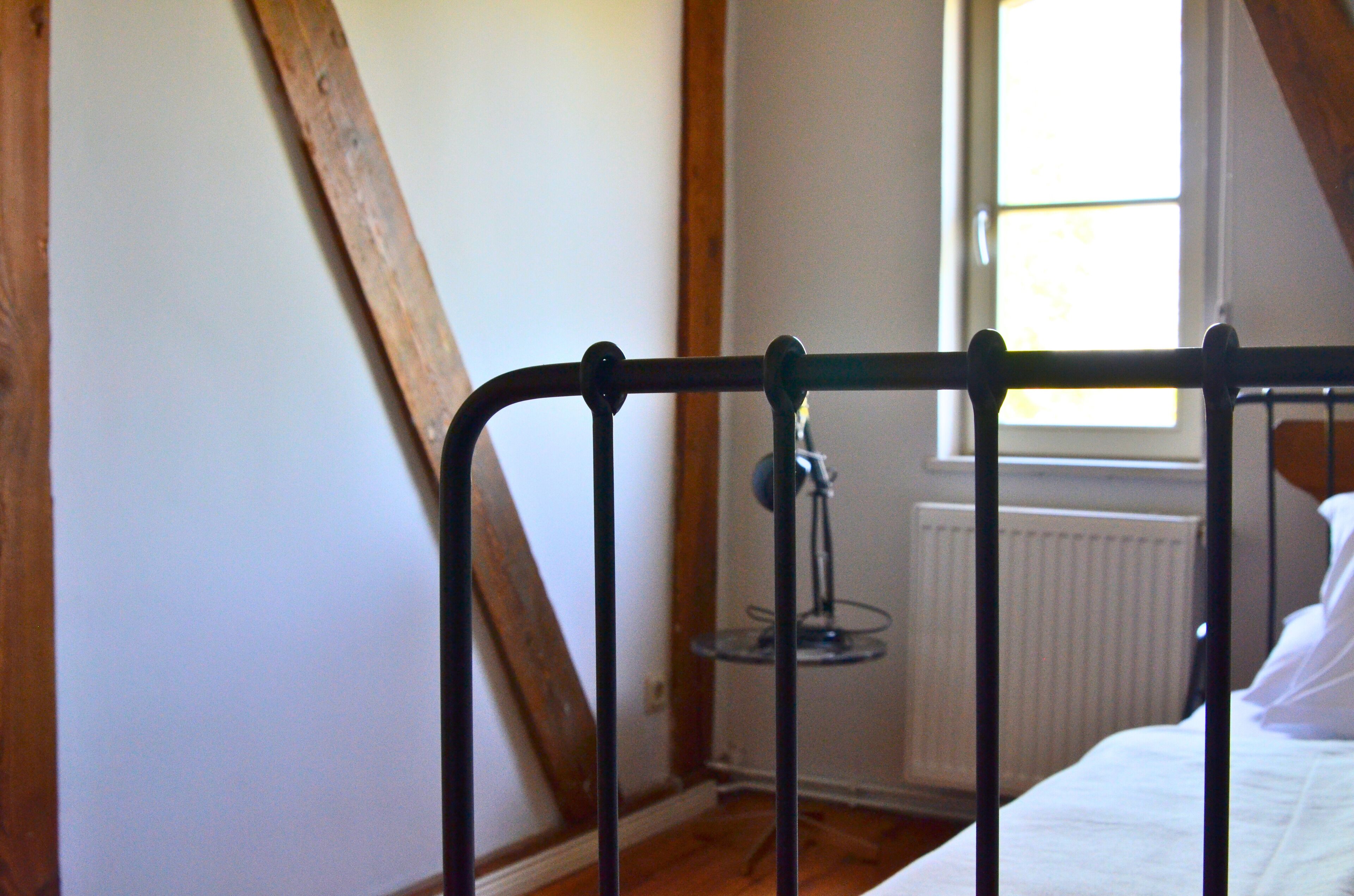 Une chambre avec un plafond en bois, un lit avec une literie blanche et une fenêtre laissant entrer la lumière naturelle.