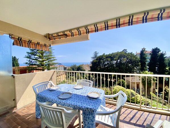 Un balcone con un tavolo apparecchiato per quattro persone, con vista su una zona residenziale e il mare.