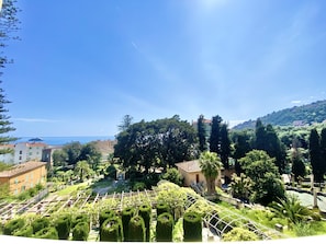 Paesaggio costiero con edifici, alberi e cielo sereno.