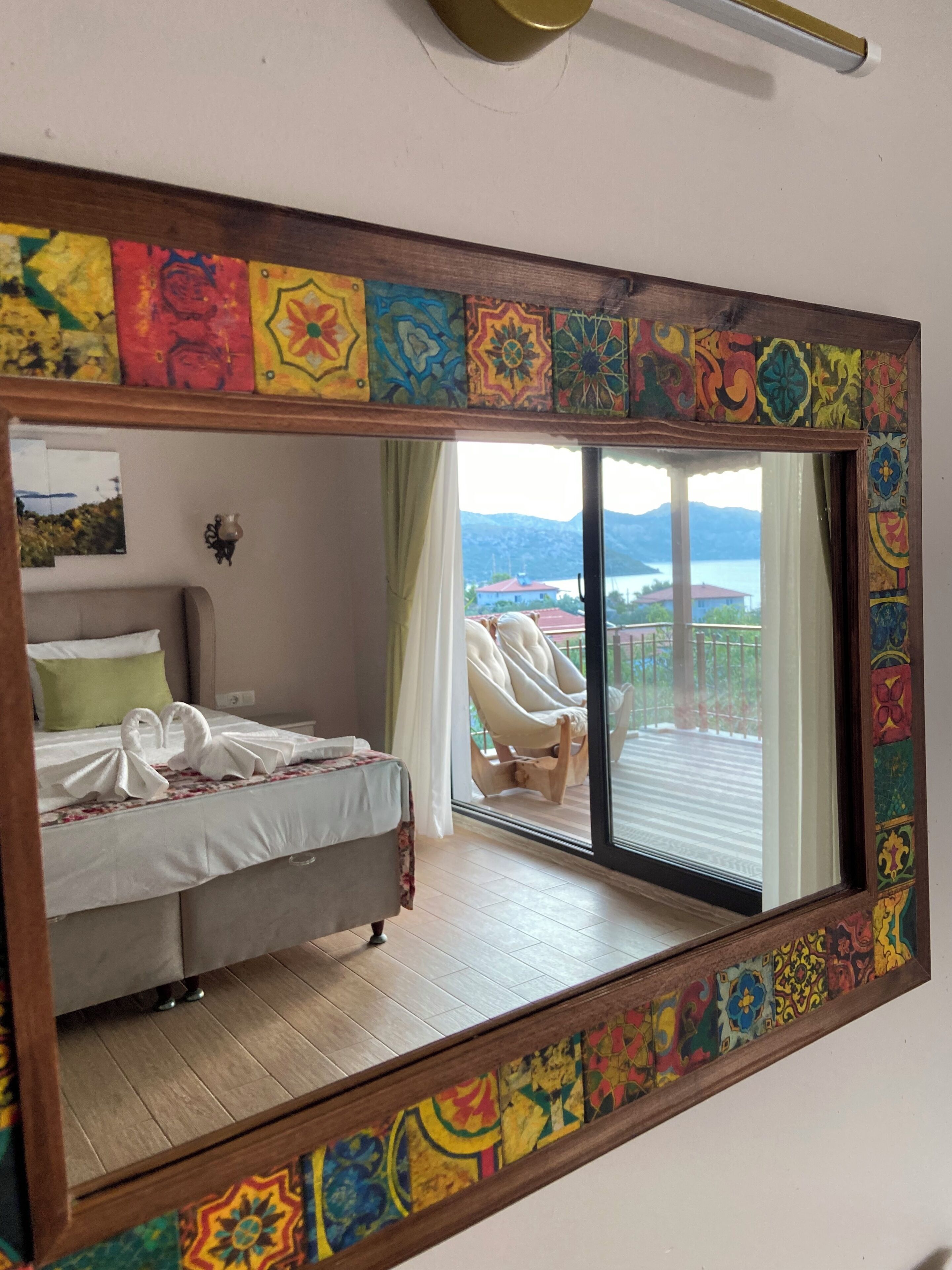 Ein Schlafzimmer mit Bett, Nachttisch, Spiegel und Blick auf einen Balkon mit Stuhl.