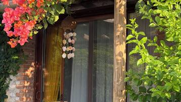 A patio with a wooden table and chairs, a glass door, and a wall covered with flowering plants.