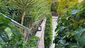 Una escalera que lleva a una casa, con montañas al fondo y abundante vegetación.