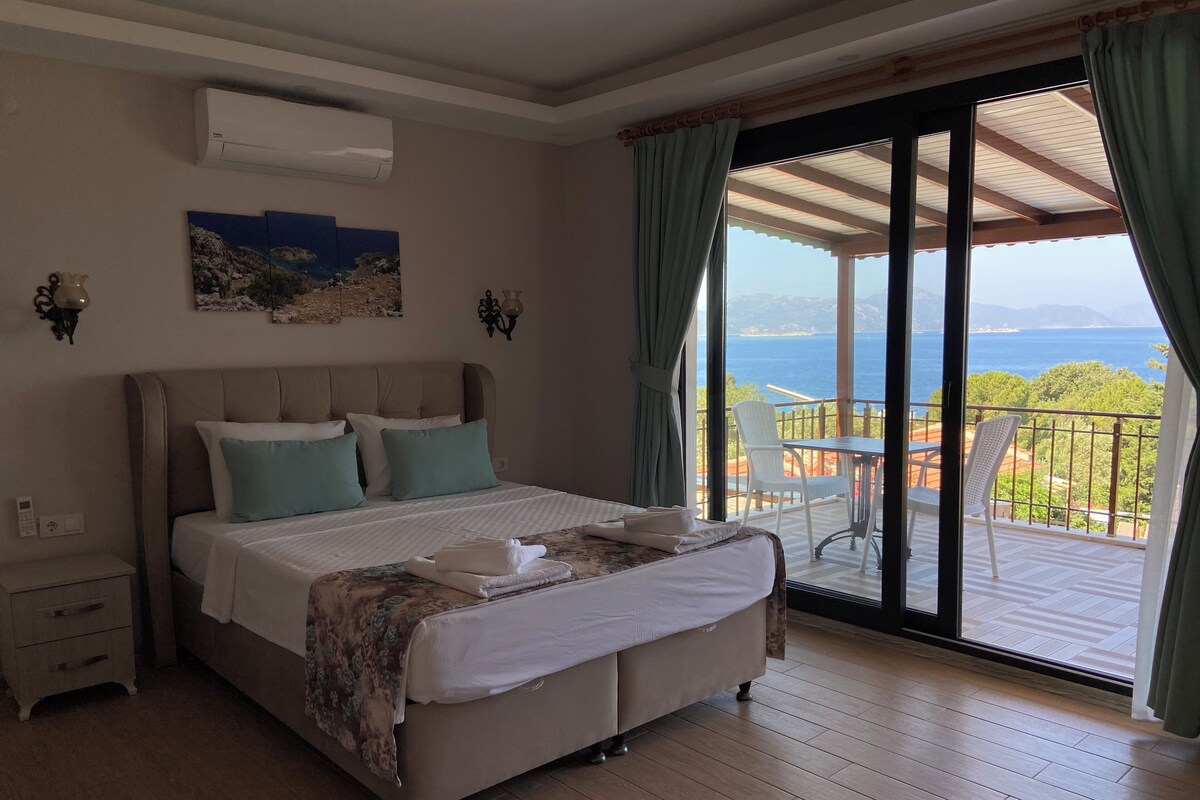 Ein Schlafzimmer mit Bett, Nachttisch, Wandairconditioner, einem Gemälde und einem Balkon mit Meerblick.