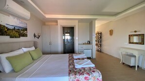 Una habitación de hotel con cama, escritorio, espejo y kitchenette.