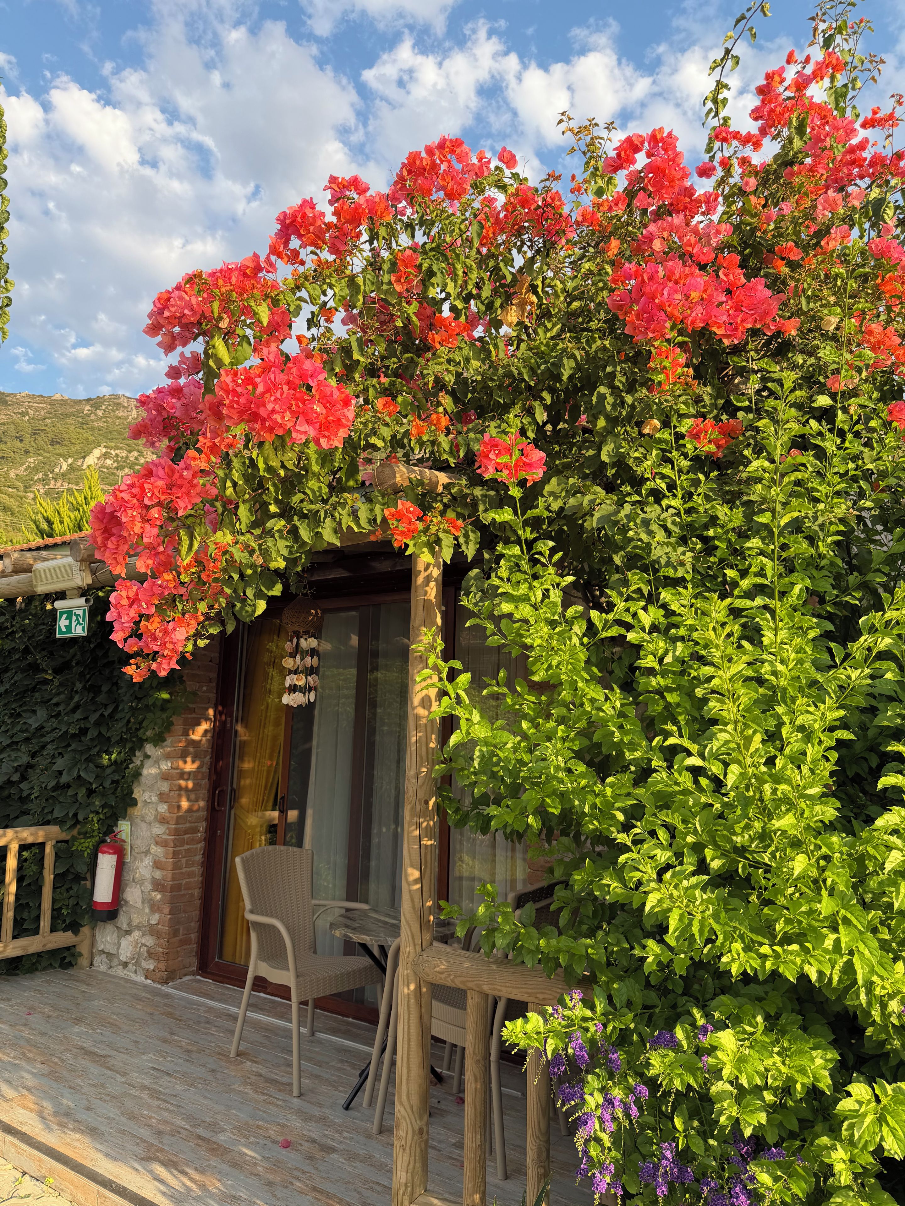 Eine hölzerne Pergola mit einem Stuhl, einer Ziegelwand und einer Glastür.