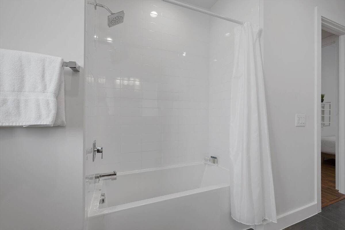 A modern bathroom with a glass-enclosed shower, a white towel hanging on the wall, and a visible shower curtain.