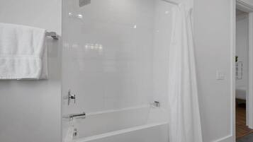 A modern bathroom with a glass-enclosed shower, a white towel hanging on the wall, and a visible shower curtain.