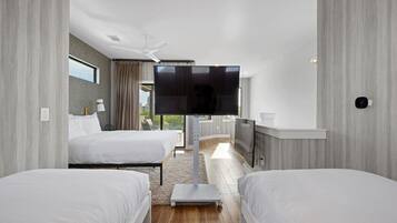 A hotel room with two beds, a flat-screen TV, a ceiling fan, and a view of the outdoors.