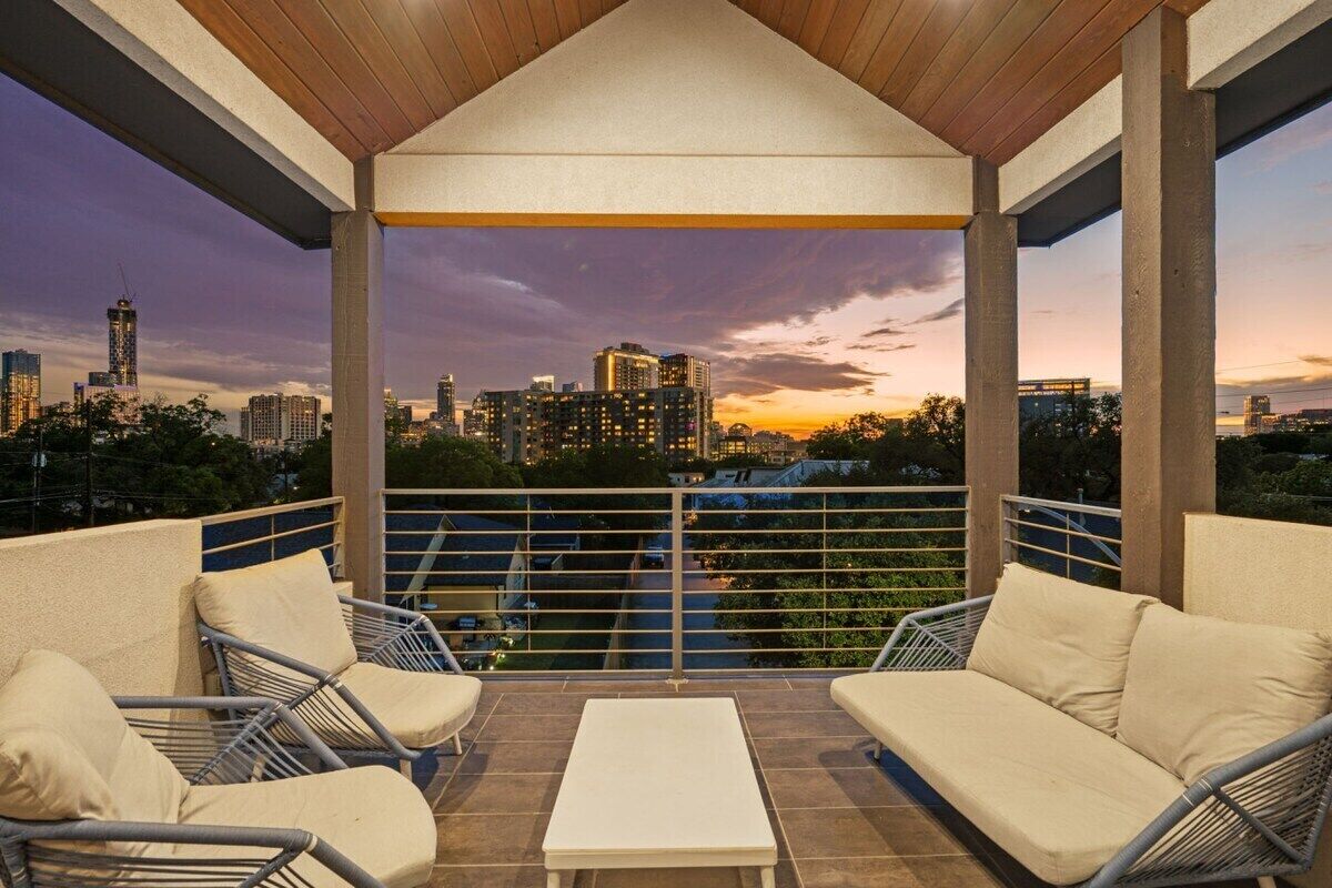 A covered outdoor seating area with a city skyline view at dusk.