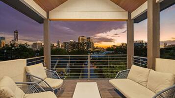 A covered outdoor seating area with a city skyline view at dusk.