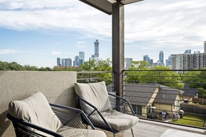 A balcony with two chairs and a view of a city skyline.