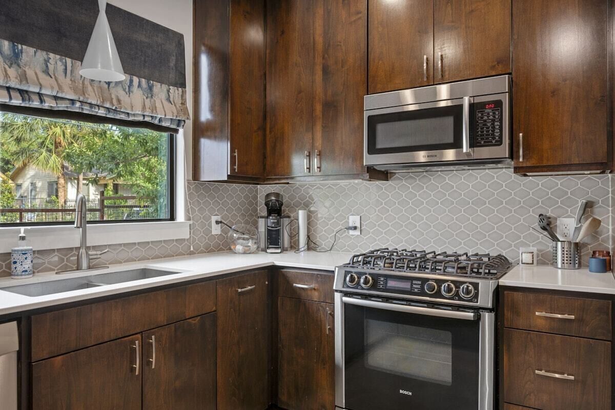 A kitchen with wooden cabinets, a Bosch gas stove, a microwave, and a coffee maker.