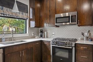 A kitchen with wooden cabinets, a Bosch gas stove, a microwave, and a coffee maker.