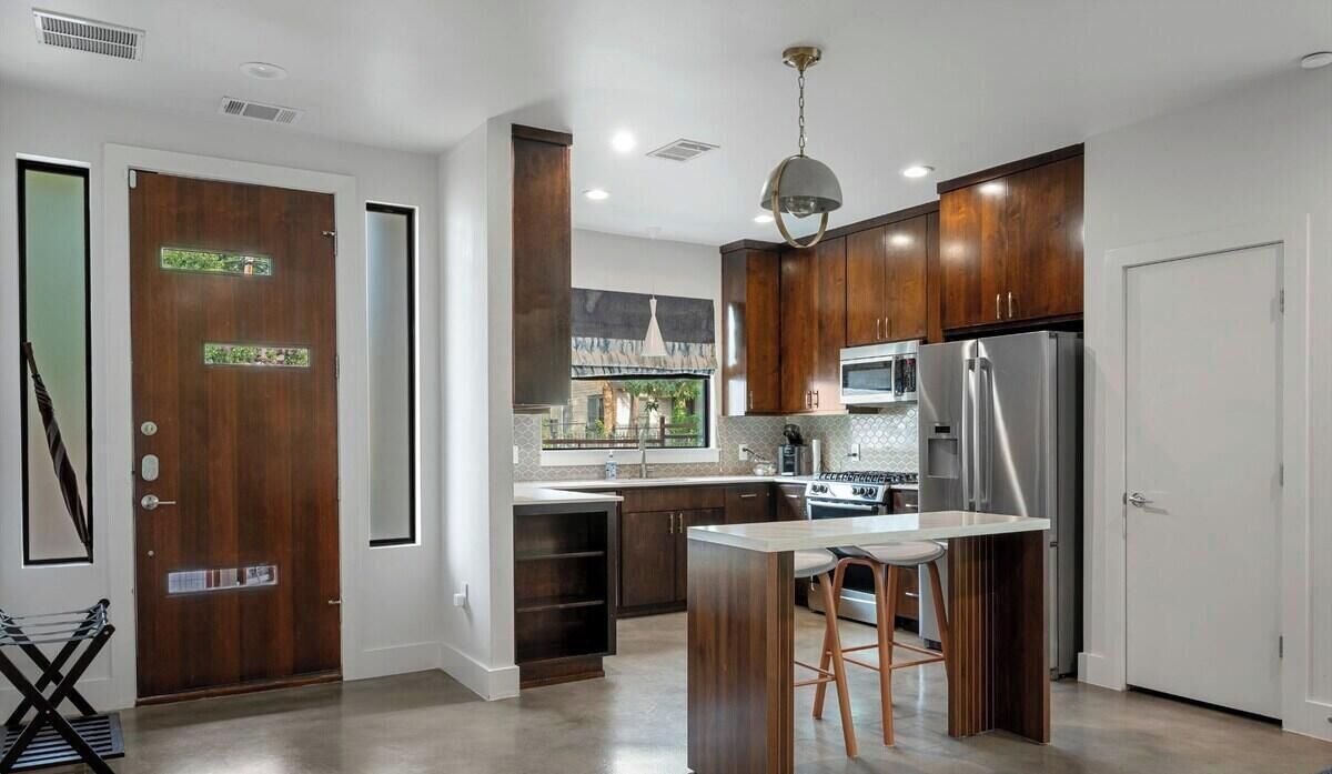 A modern kitchen with dark wood cabinets, stainless steel appliances, and a central island with bar stools.