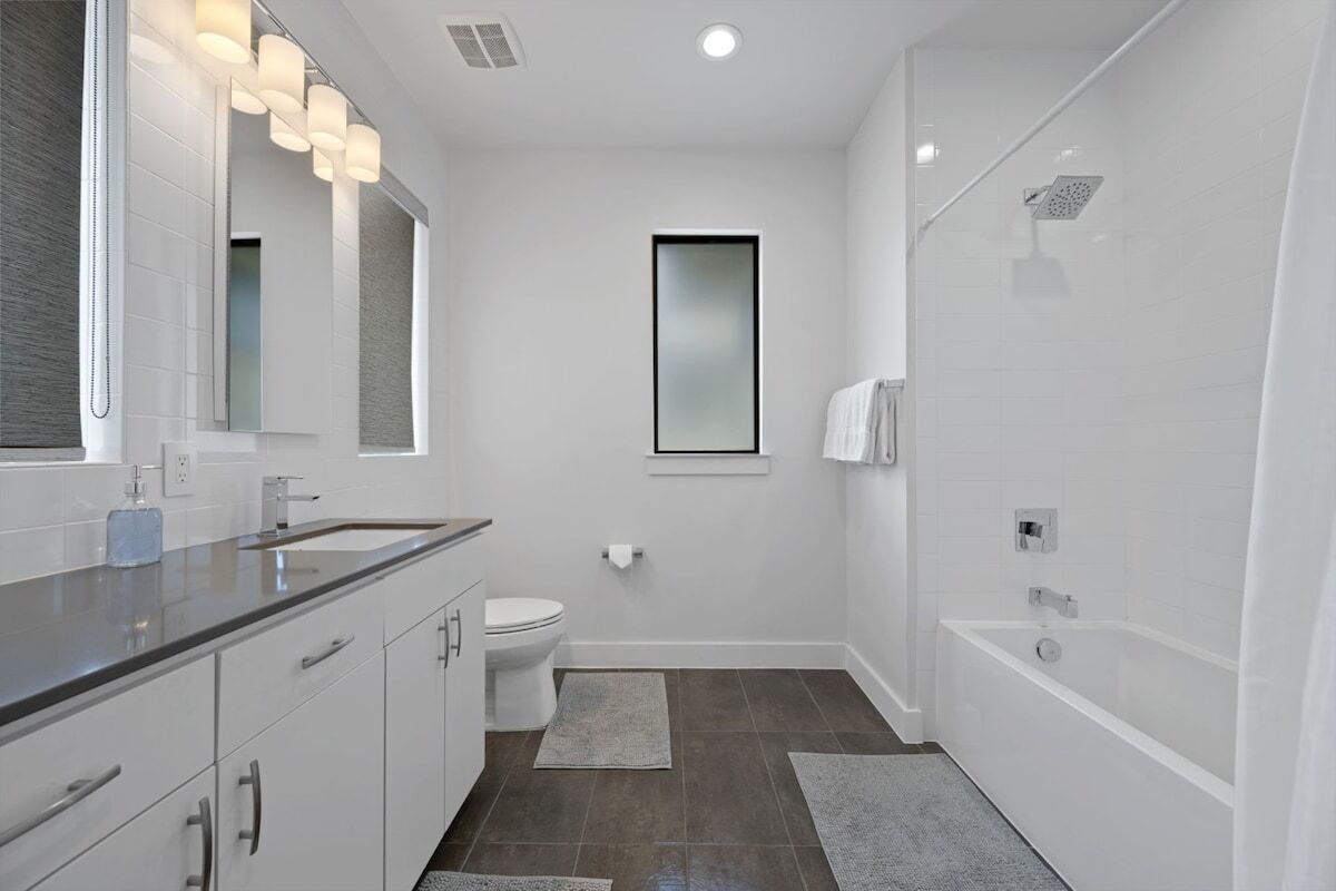 A modern bathroom with a large mirror, a toilet, a bathtub, and a shower.