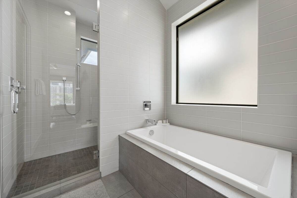 A modern bathroom with a walk-in shower, a large bathtub, and a wall-mounted mirror.