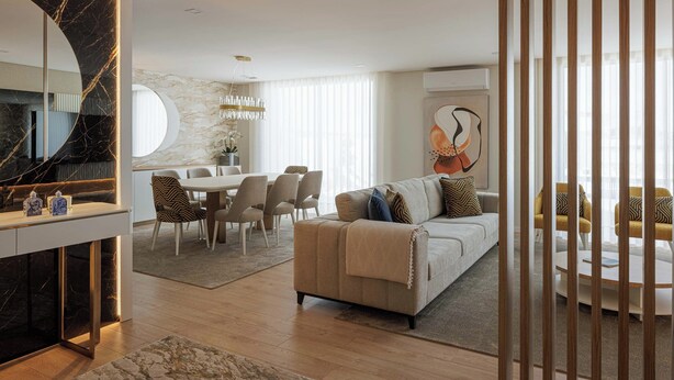 A modern living room with a sofa, dining area, and a large mirror.