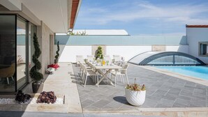 An outdoor patio with a pool, seating area, and potted plants.