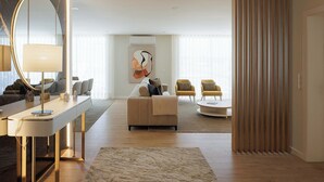 Un salon moderne avec un canapé, des fauteuils, une table basse, un grand miroir et un tableau accroché au mur.