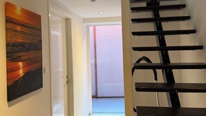 Ein Flur mit Treppe, einem Gemälde und einer Tür, die auf einen Balkon führt.