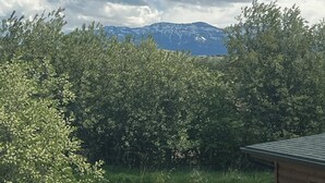 A view of a mountain range with snow-capped peaks under a partly cloudy sky. - Southfork Guesthouse (Cody)