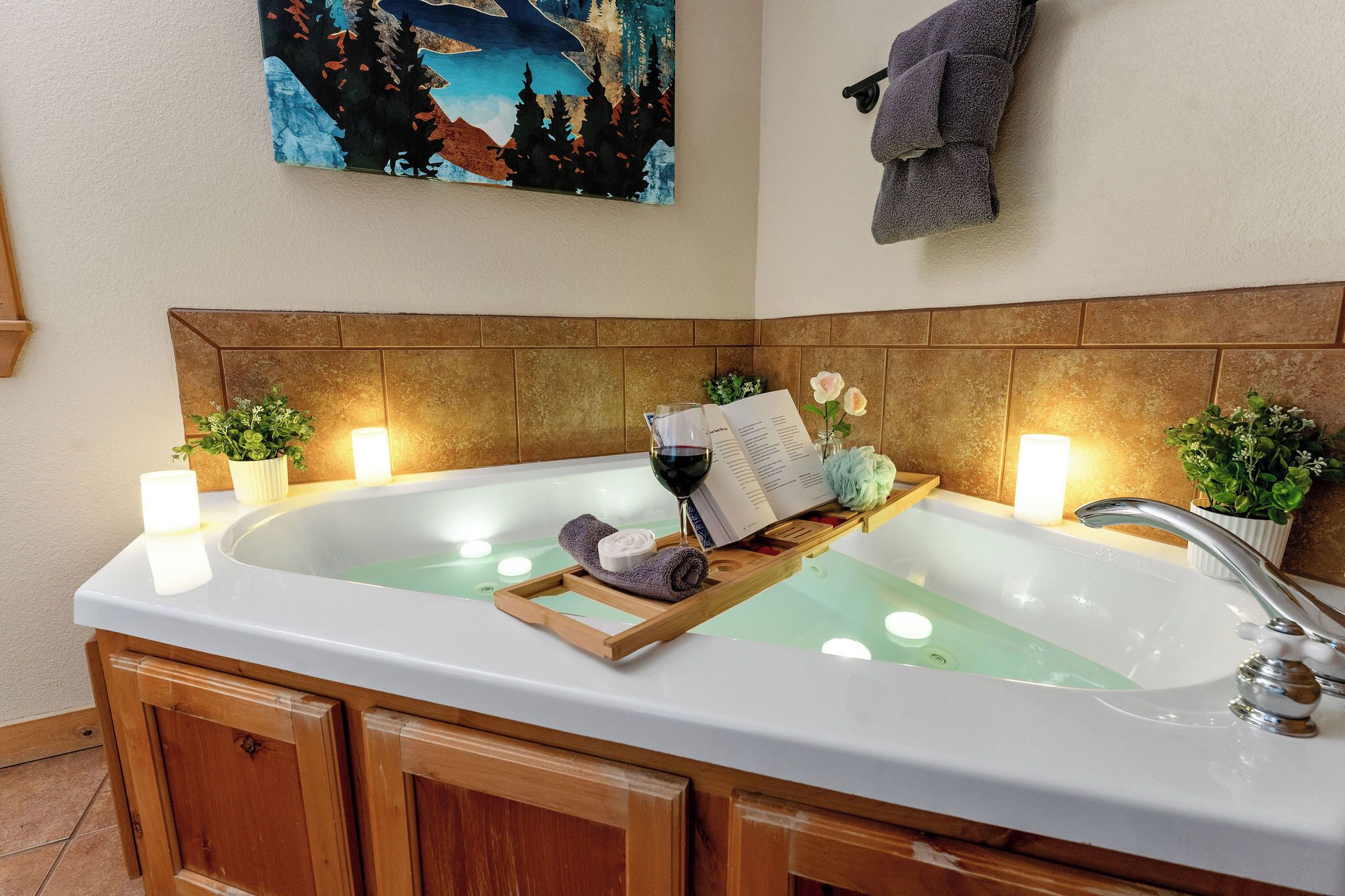 A bathroom with a large bathtub, wooden cabinets, and a painting on the wall.