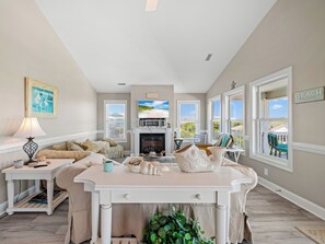 Un salon avec une cheminée, une table à manger et une vue sur la plage.