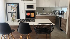 A modern kitchen with a central island, black chairs, and a dining table.