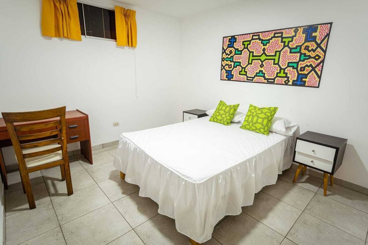 Una camera da letto con un letto, una scrivania, una sedia e un comodino.