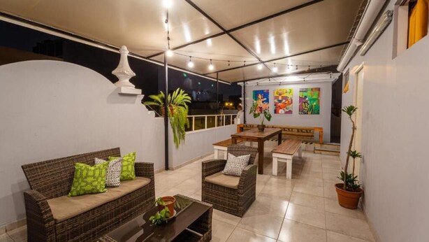 A rooftop terrace with wicker furniture, a dining table, and potted plants. - Casa Águila y Condor (Lima)
