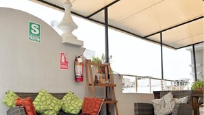 A furnished outdoor seating area with wicker sofas, a glass coffee table, and a white ceiling structure. - Casa Águila y Condor (Lima)