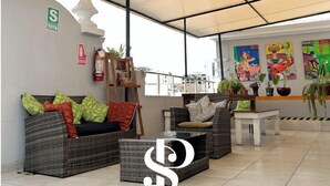 An open-plan living area with a covered patio, wicker furniture, and a fire extinguisher on the wall. - Casa Águila y Condor (Lima)