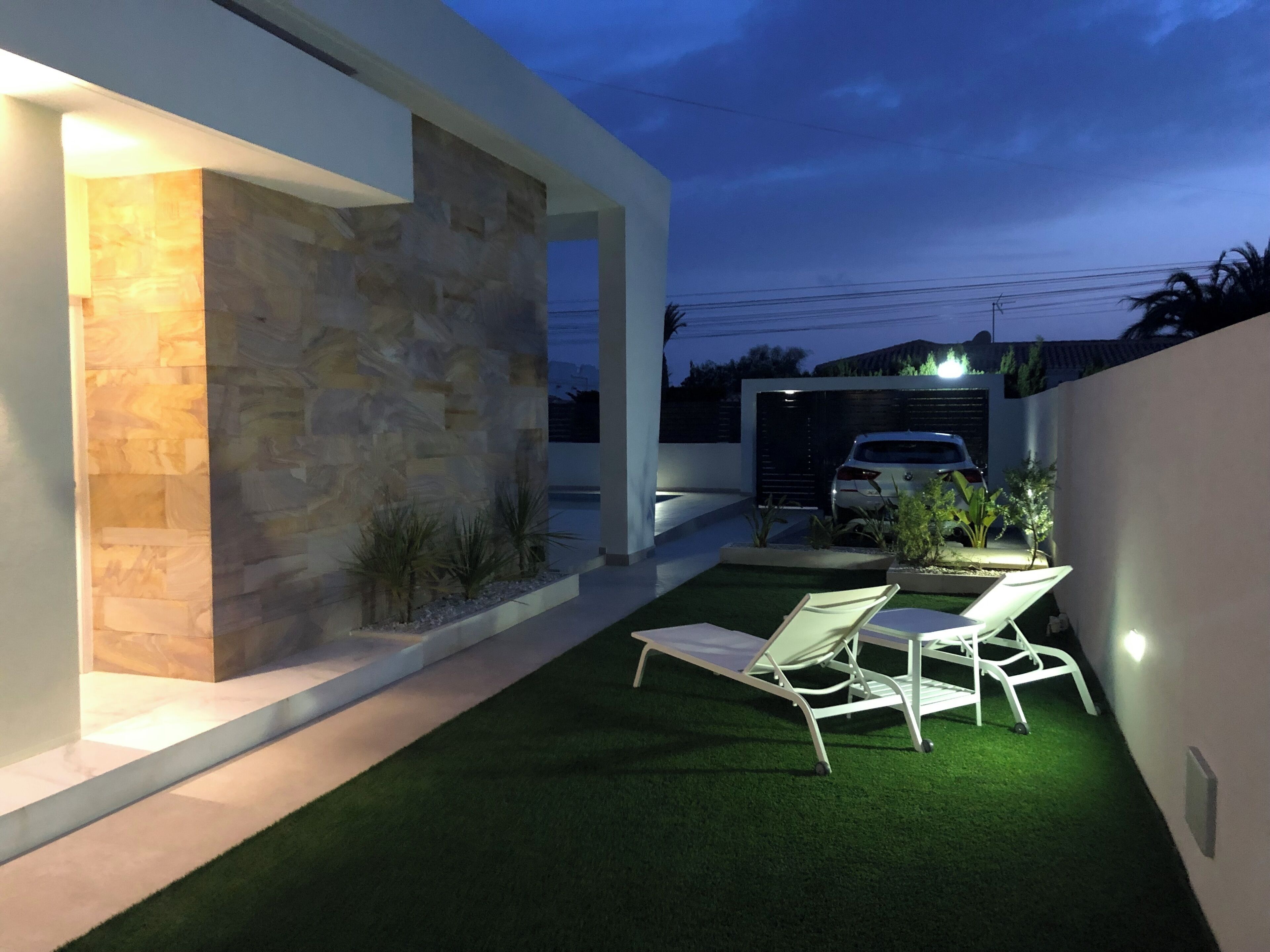 A modern house with a stone facade, a lawn, and outdoor seating.