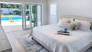 A bedroom with a large bed, a ceiling fan, and a view of a swimming pool through glass doors.