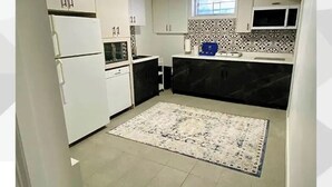 Une cuisine de taille réduite avec des meubles blancs, un plan de travail noir et un pare-feu décoré.