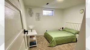 Une chambre à coucher avec un lit, une petite table, une fenêtre et une horloge au mur.