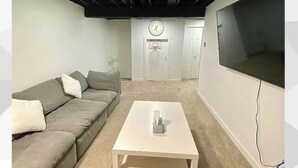 Un salon avec un canapé, une table basse, une horloge et un téléviseur.