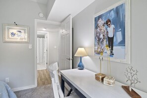 Een moderne slaapkamer met een bed, een bureau en een stoel. Er hangt een schilderij aan de muur en op het bureau staat een lamp.