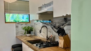 Una cucina moderna con un piano di lavoro in legno, un lavello, un fornello e una finestra vista sul verde.