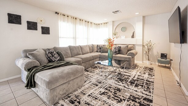 A modern living room with a sectional sofa, a small coffee table, and a patterned rug. - Chic Vegas House w/Game Room + BBQ (North Las Vegas)